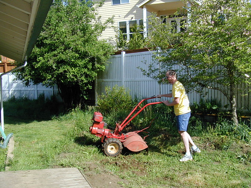 Man using a rototiller in his yard