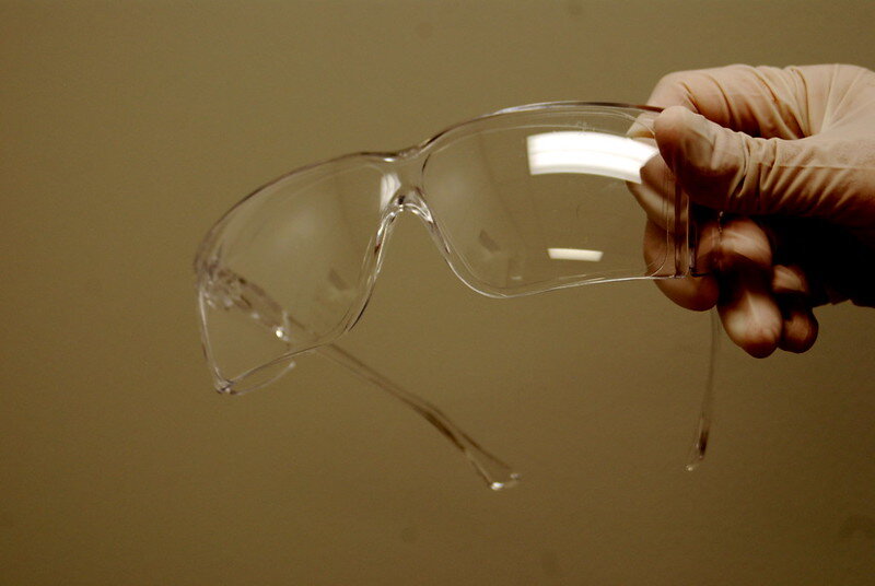 safety glasses being held by someone