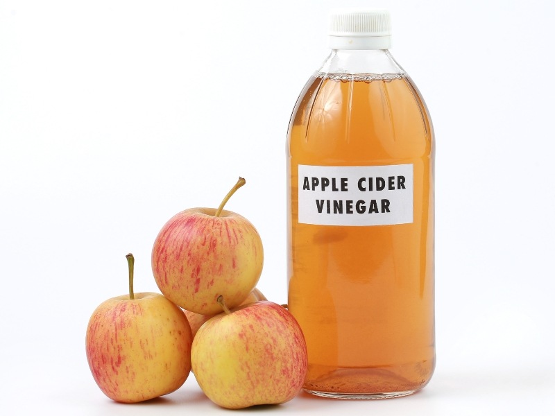 apple cider vinegar next to a stack of apples